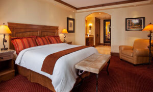 Siebert Suite king bed, Chair and walking bathroom featuring rich creams and red décor at our Vail hotel