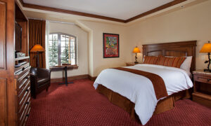 Vail Village room with window, king bed chair and tv armoire at Tivoli Lodge