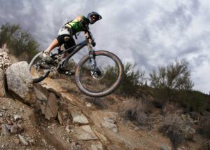 male mountain biker rides down rough mountain trail Tivoli Lodge Vail Colorado