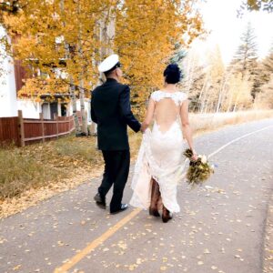 bride and groom elope and walk down bike path during fall day Tivoli Lodge Vail Colorado