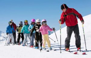 ski instructor gives lessons to kids during ski school Tivoli Lodge Vail Colorado