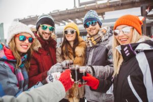 five friends enjoy a warm drink on a chilly day outside Tivoli Lodge Vail Colorado