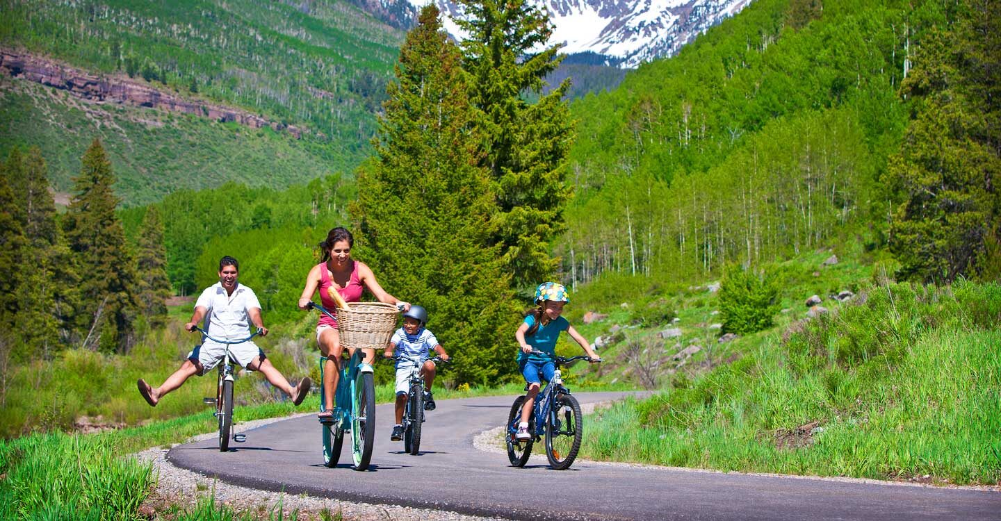 family of four goes on a bike ride on paved trail Tivoli Lodge Vail Colorado