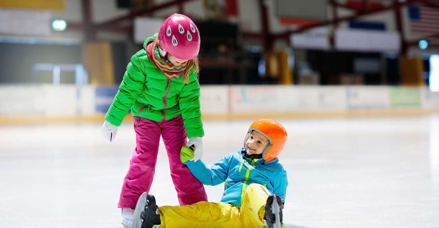 young girls learn to ice skate with one helping the other up off the ice Tivoli Lodge Vail Colorado