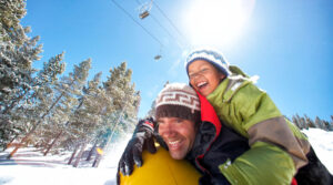 father and child enjoy a snow tube ride at Vail mountain Tivoli Lodge Vail Colorado