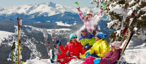 Group of friends relax in the snow on top of a mountain with skis upright in the snow Tivoli Lodge Vail Colorado